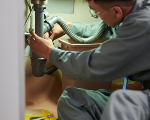 Plumber unclogging kitchen sink, household service